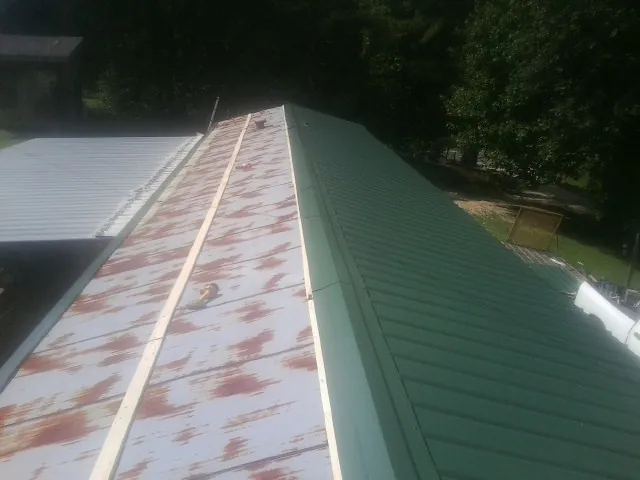 Old rusted panels beside newly installed green metal roofing — Wind Damage Roof Repair by Roofing Brothers in Columbus