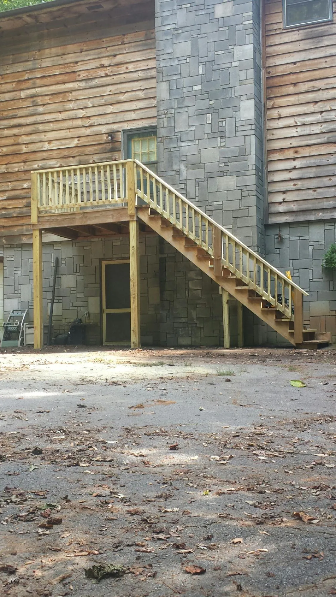New pressure treated deck and stair landing on a log home in Columbus